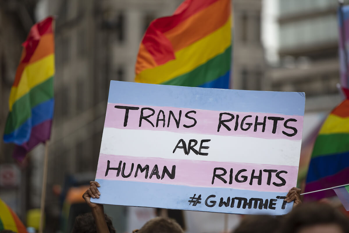 A person holding a pro transgender banner at a gay pride event