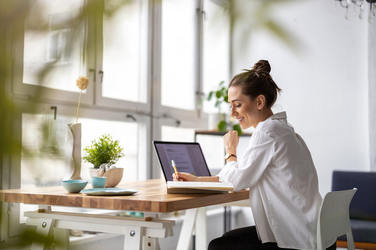 A woman working from home writing notes