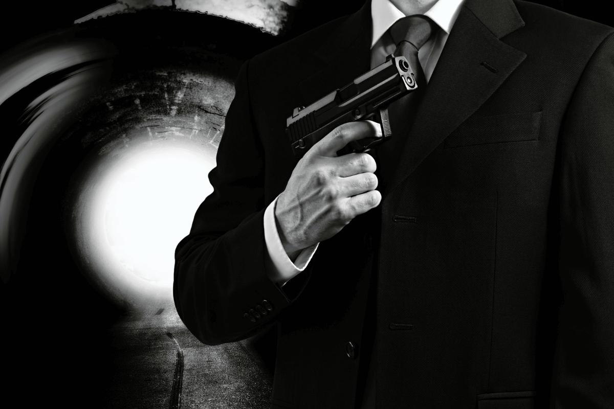 Black and white photo of a male in a suit holding a gun- James Bond movie concept