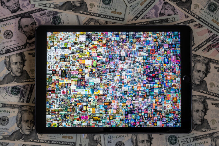 Tablet with Beeple pattern " EVERYDAYS: THE FIRST 5000 DAYS" placed on dollar bills. Collage art signed with NFT token. Concept. Stafford, United Kingdom, March 13, 2021.