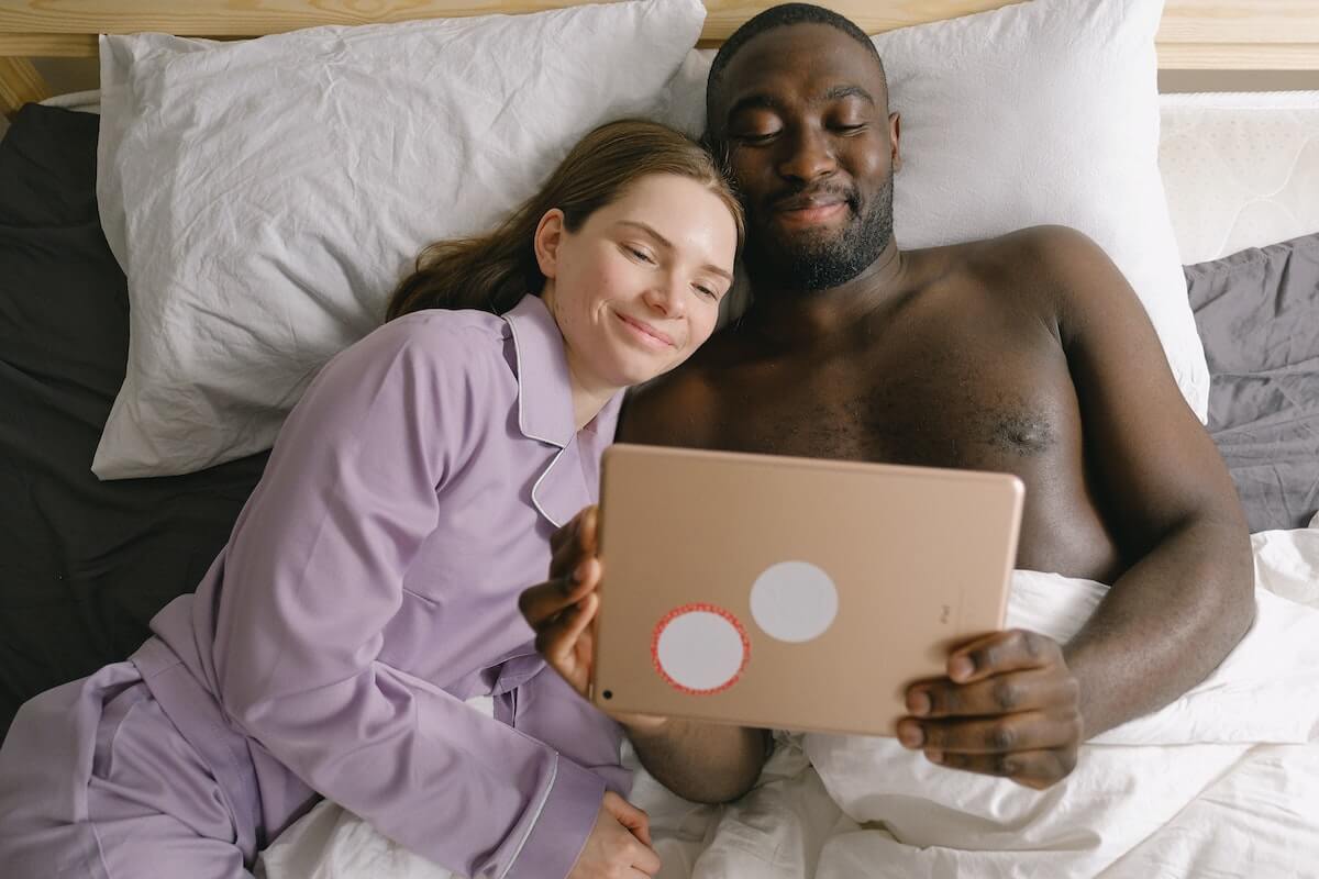 A couple in bed looking at a tablet