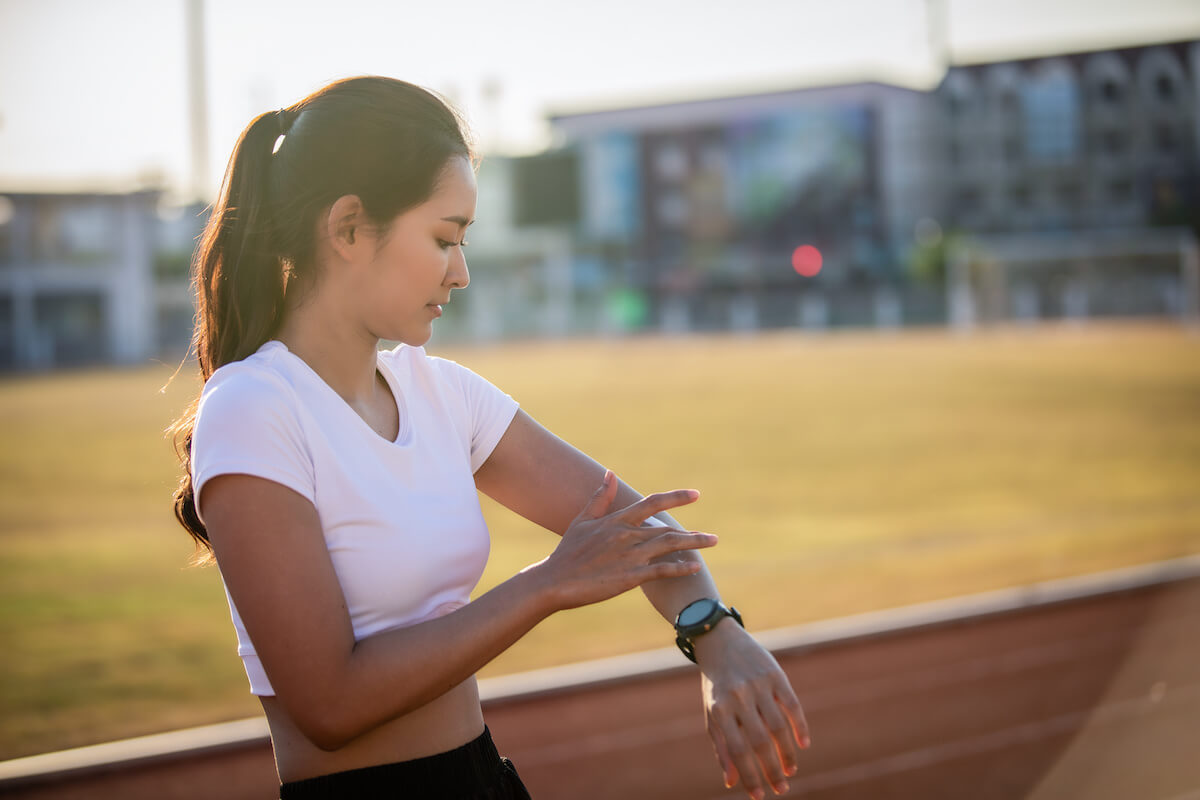 Asian Woman applying and spraying sunscreen cream on skin before a run.