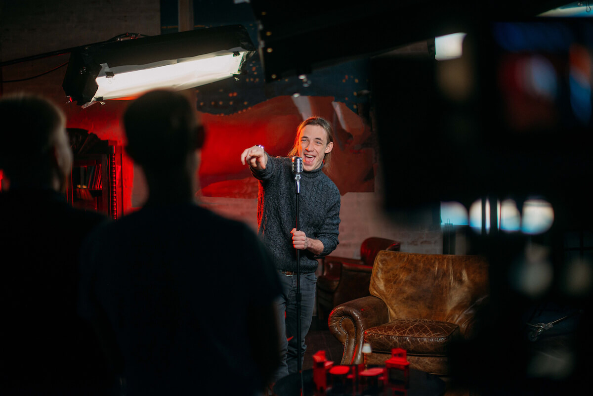 A young male stand-up comedian on stage at the microphone. 