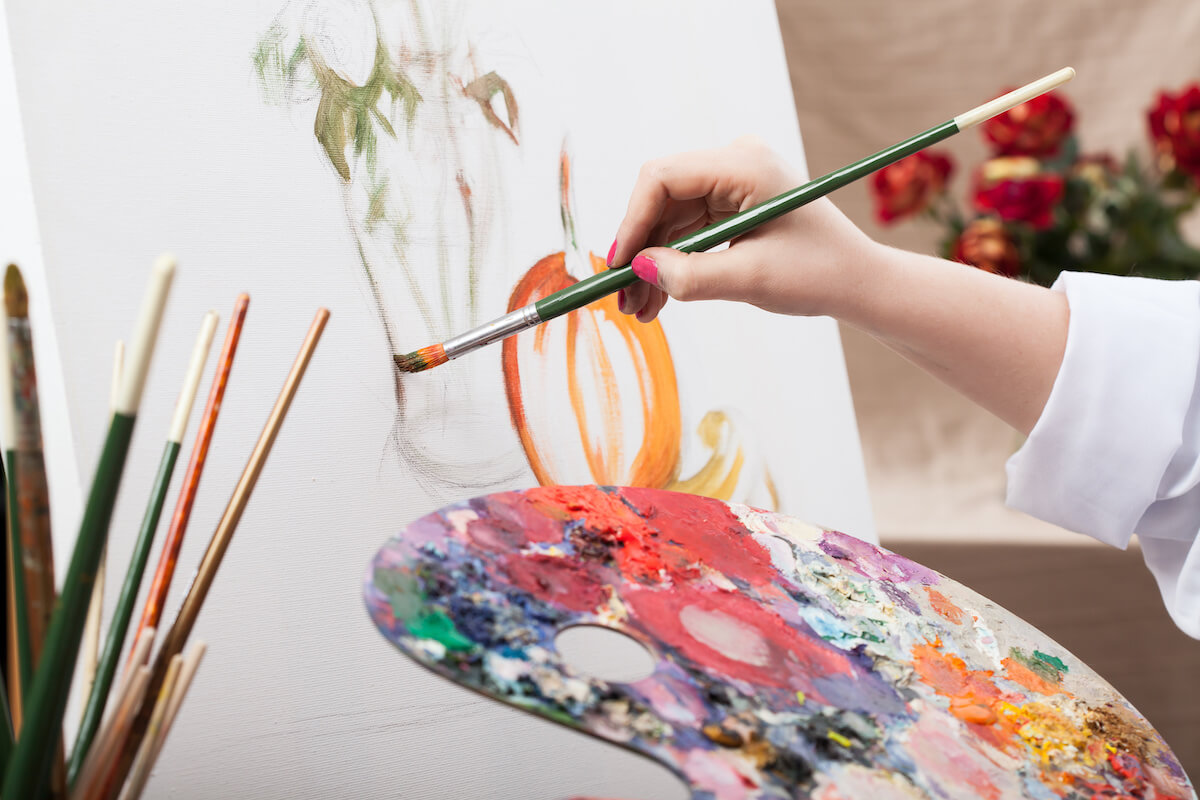 A closeup of an artist with a brush painting a picture.