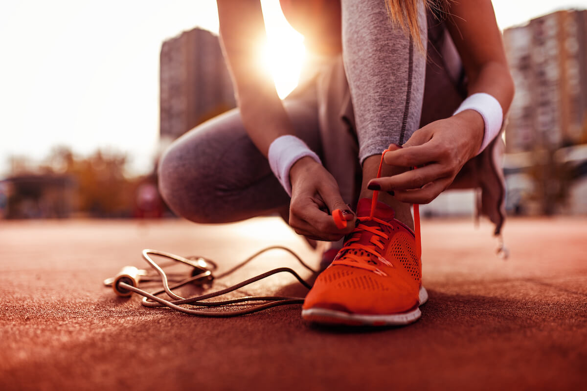 Female runner tying her red shoes and preparing for a jogging.