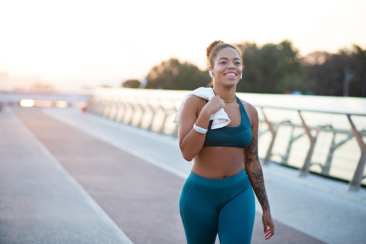 Tattooed young woman holding towel while going home after running in the morning