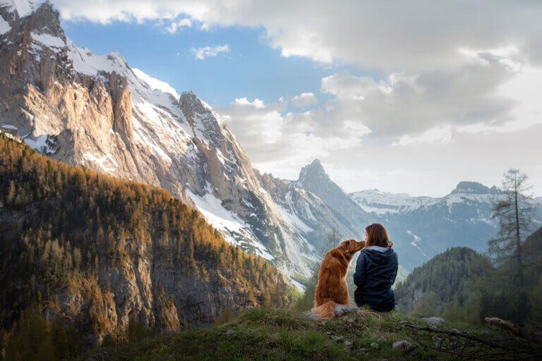 Girl with a Duck Toller dog in the mountains.
