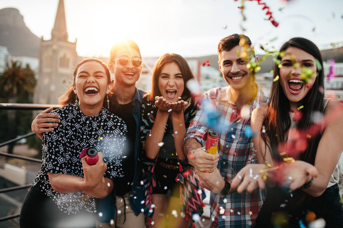 Group of friends enjoying party and throwing confetti. 