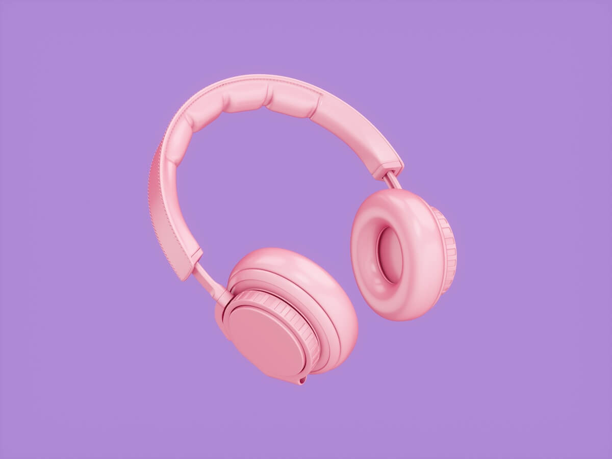 Pink over-the-ear headphones isolated on purple background. 