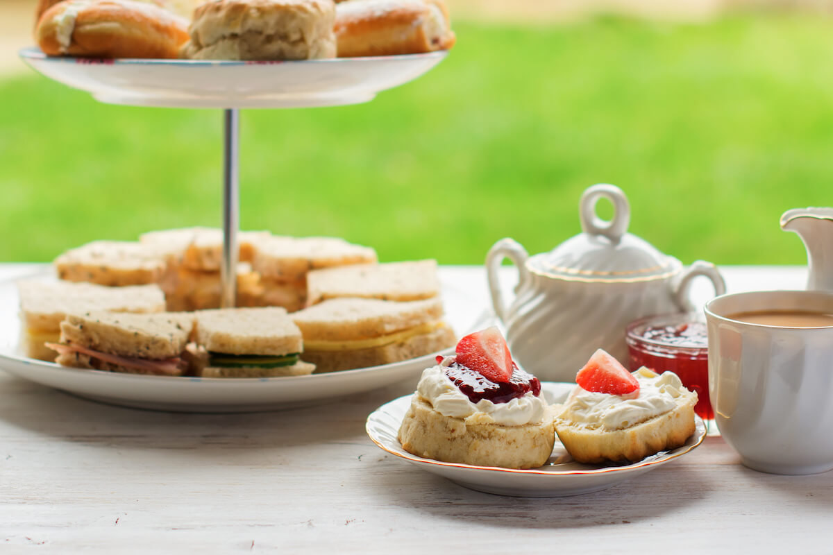 English afternoon teas in the garden cafe: scones with clotted cream and jam, strawberries, with various sandwiches on the background