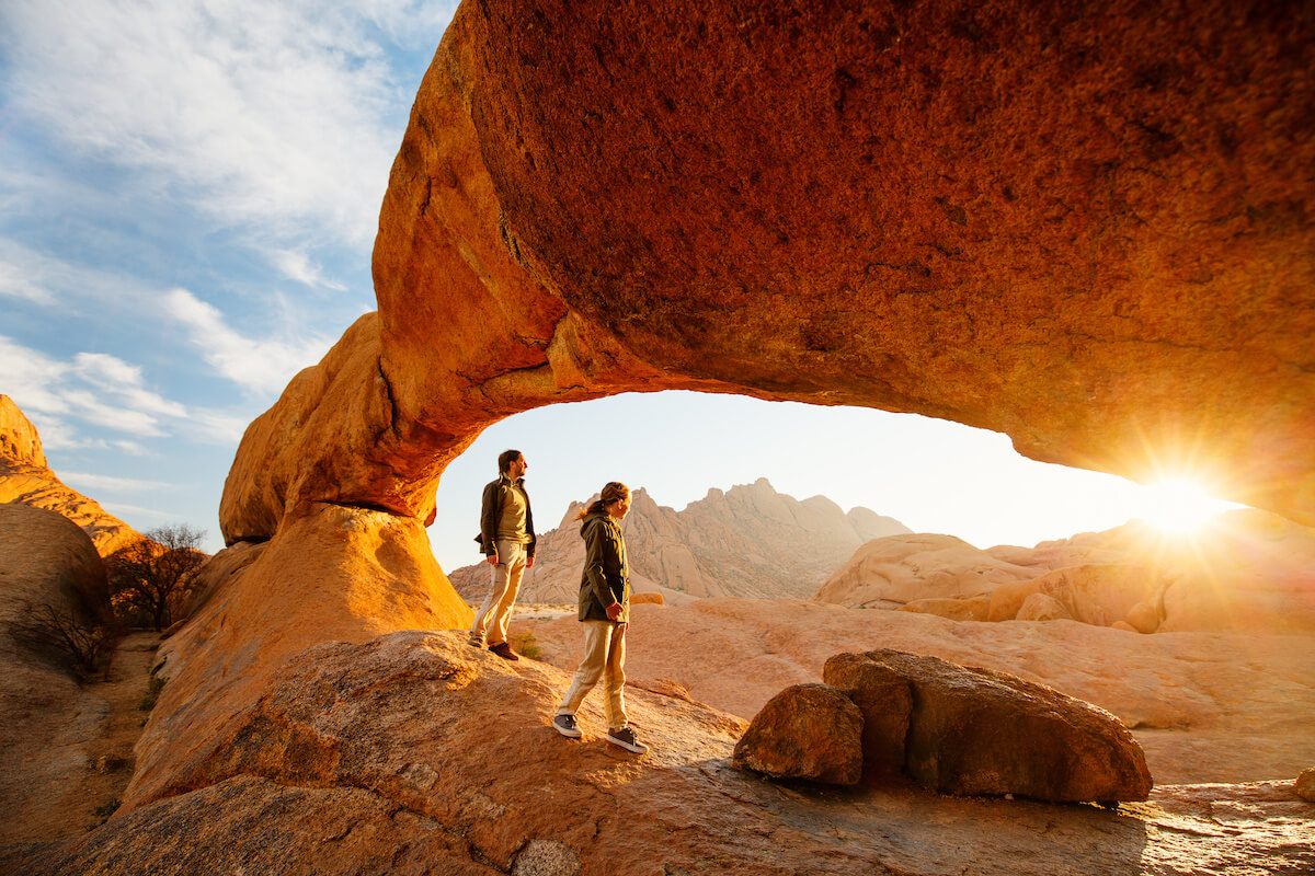 Family father and daughter enjoying sunrise in Spitzkoppe area with picturesque stone arches and unique rock formations in Damaraland Namibia