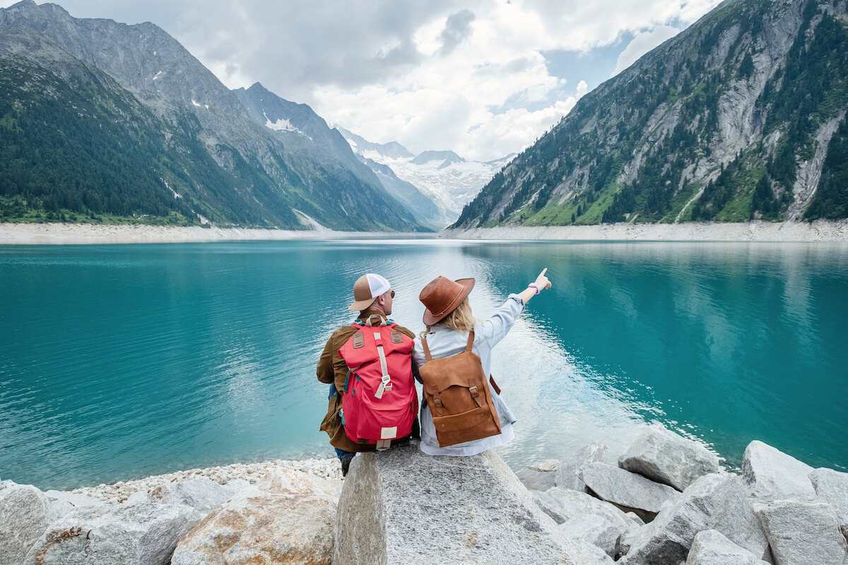 Travelers couple look at the mountain lake.