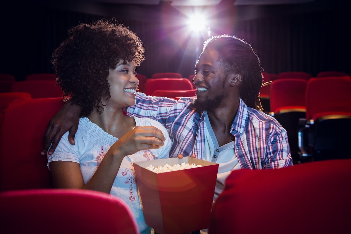 Happy young couple looking at each other in movie theatre