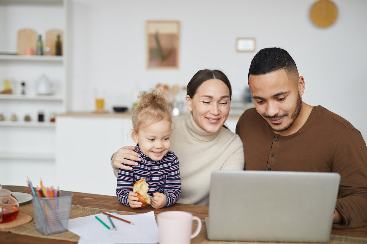 Portrait of smiling mixed race family using laptop together while shopping online