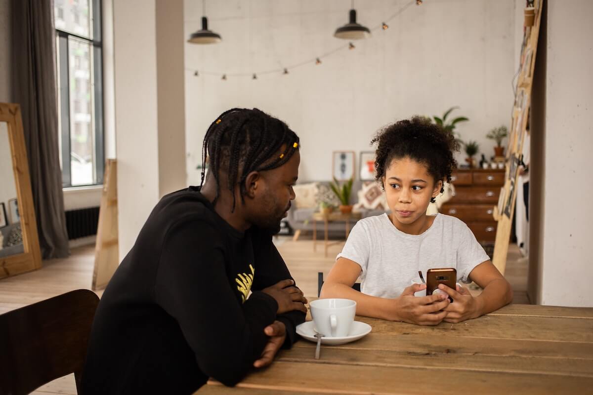 Father and daughter talking at the table in a cafe.