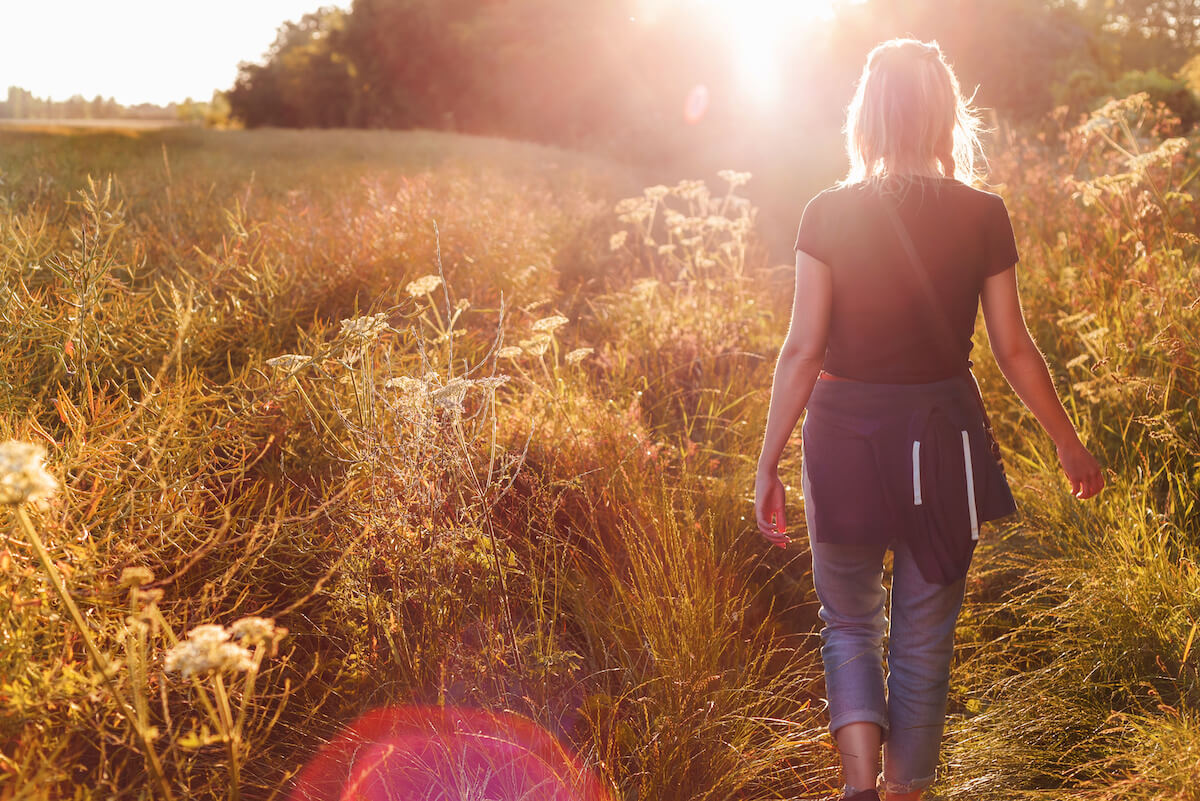 Female walking in nature with sunset in the background