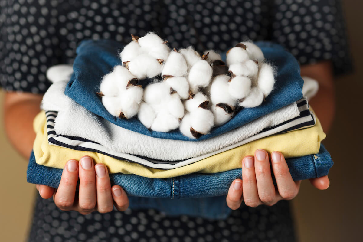 Hands hold a stack of organic clothing and cotton colors. Eco friendly fabric shop.