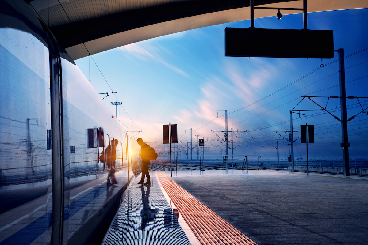 Man at train stop at railway station with sunset