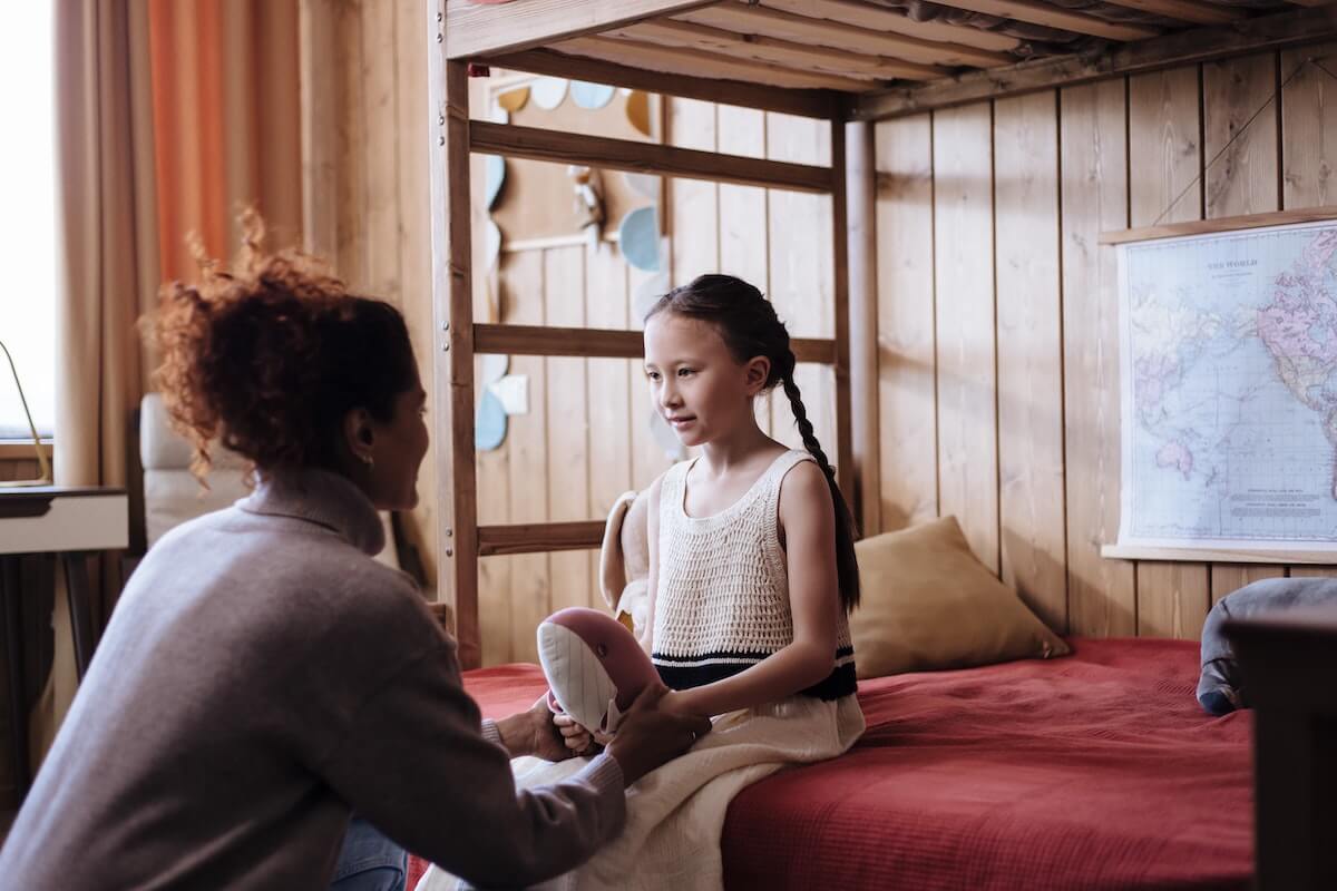 A mother talking to daughter in her room.