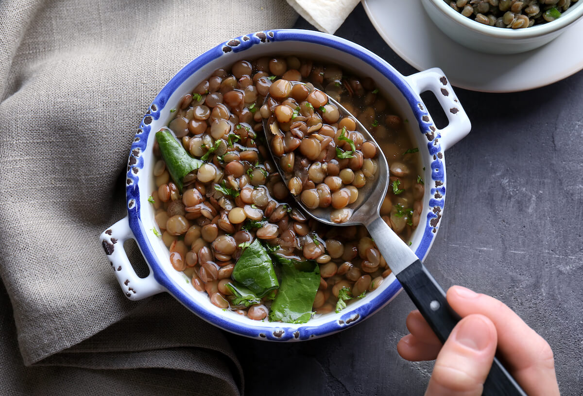 Hand of woman eating tasty lentil dish, closeup