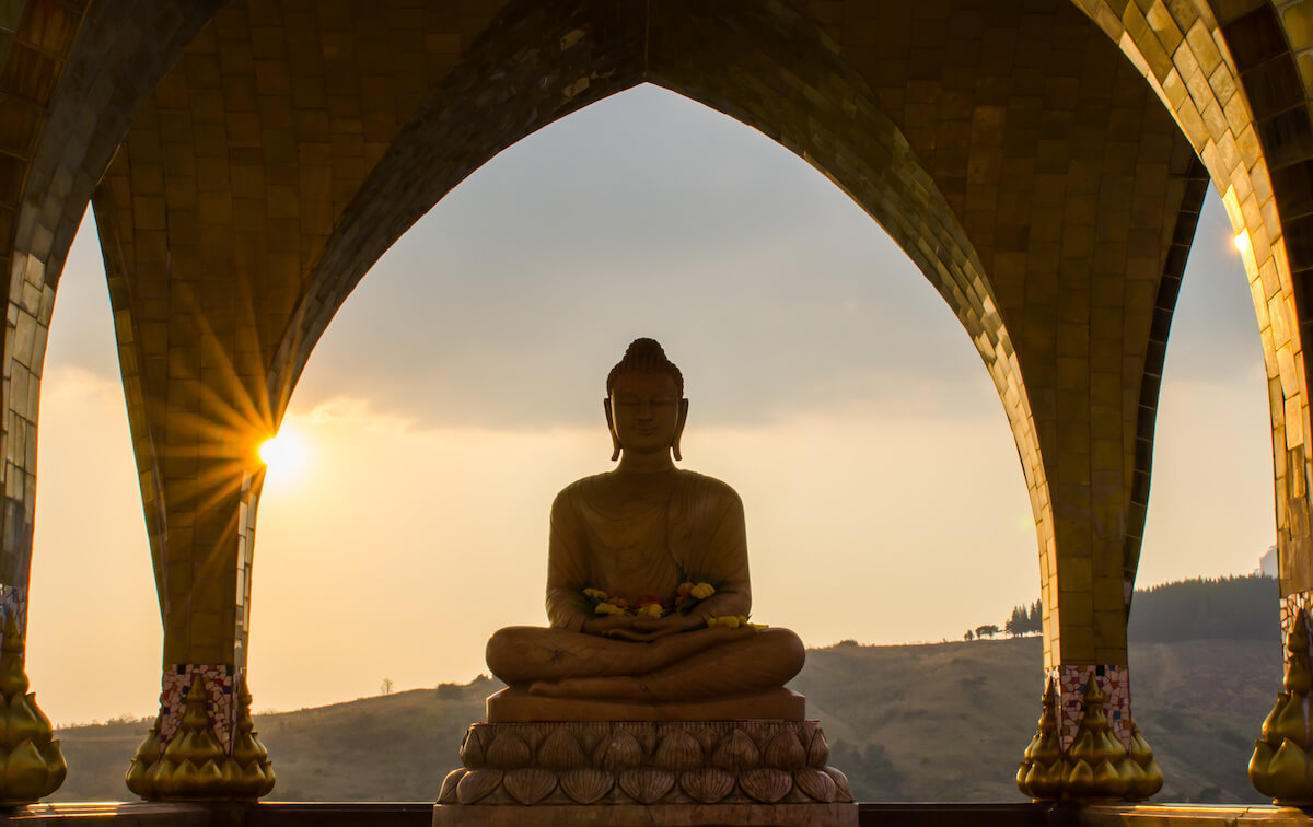 A Buddha statue with sunset in the backgroud.