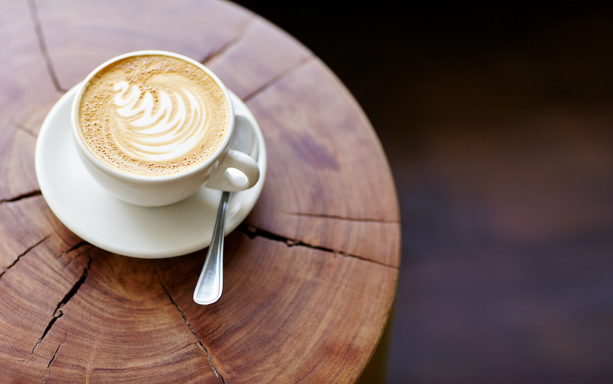 Closeup of a cappucino on a wooden stump with beautiful natural patterns