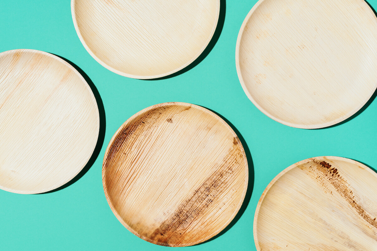 Disposable tableware from natural materials, wooden spoon, fork on yellow background.