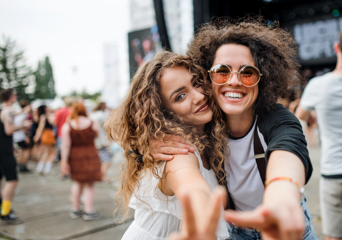 Young girl friends at summer festival, posing for photograph.