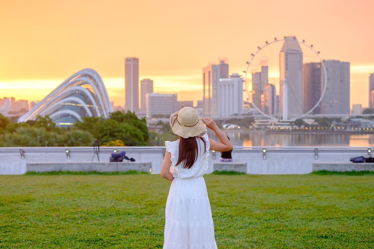 Young Woman traveling with hat at Sunset, happy Asian traveler visit in Singapore city downtown.