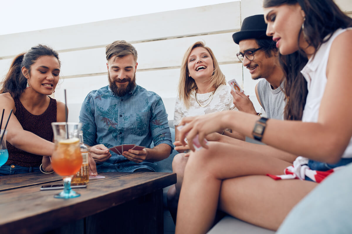 Group of friends sitting at a wooden table and playing cards. 