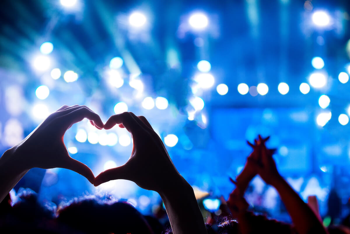 Crowd of Audience at during a concert with silhouette of a heart shaped hands