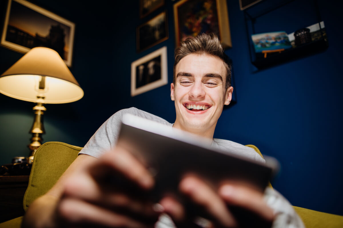 Smiling adolescent playing video games on smartphone.