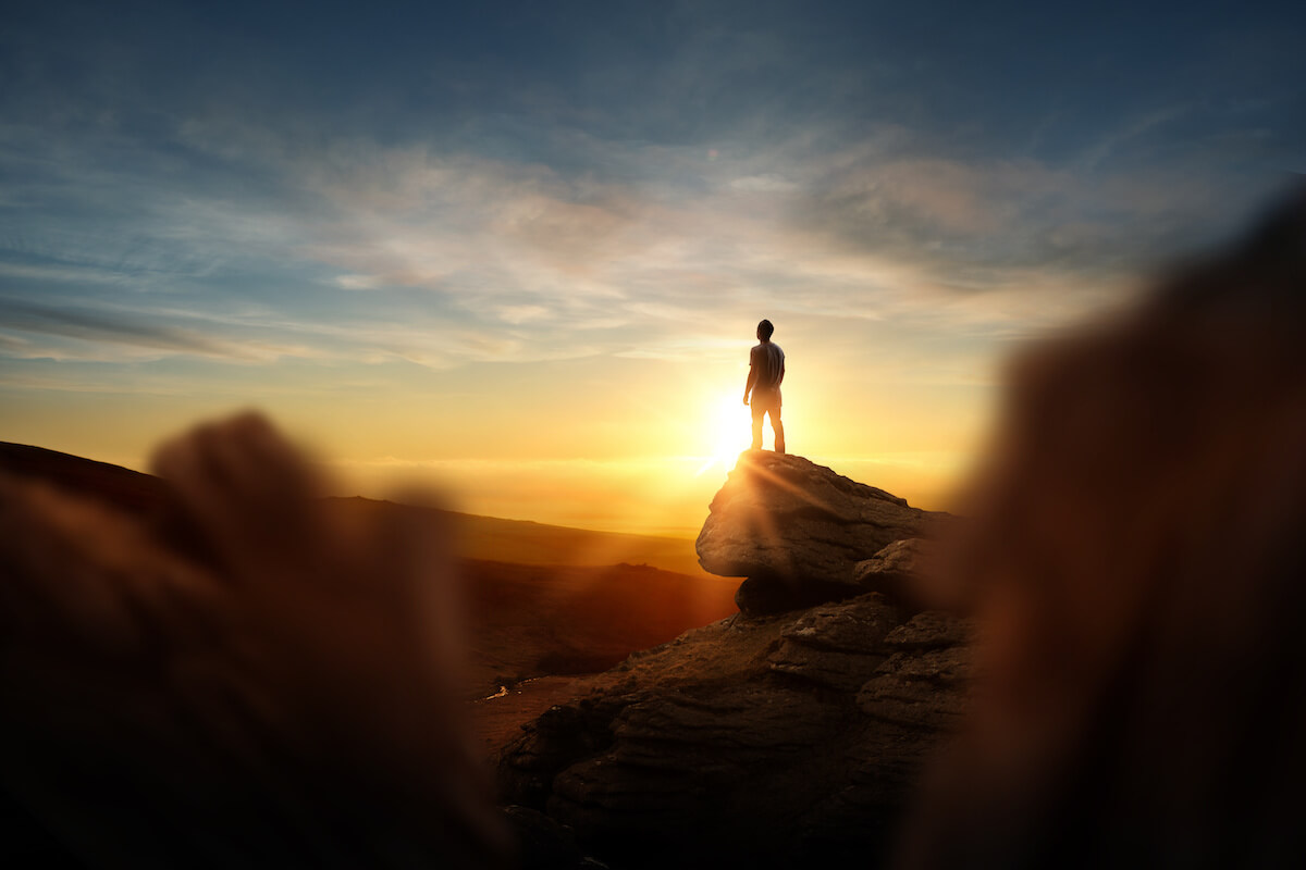 A man standing on top of a mountain watching the sunrise.