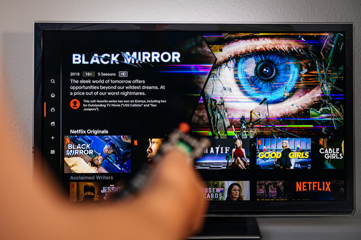 Senior man hand holding remote control watching the Black Mirror on Netflix