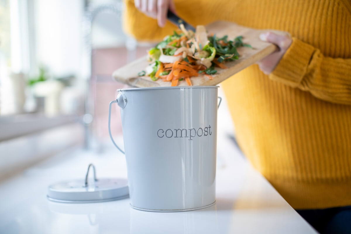 Close Up Of Woman Making Compost From Vegetable Leftovers In Kitchen