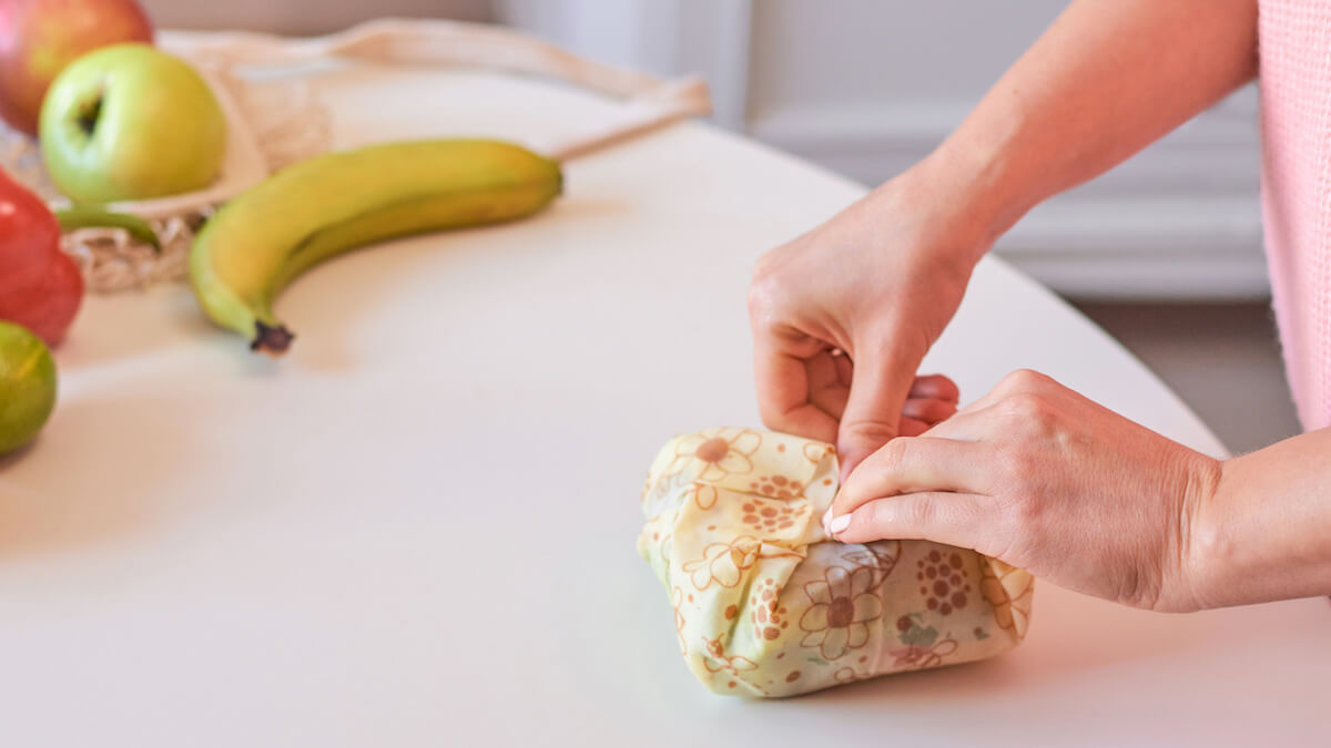 Woman hands wrapping a healthy sandwich in beeswax food wrap. 