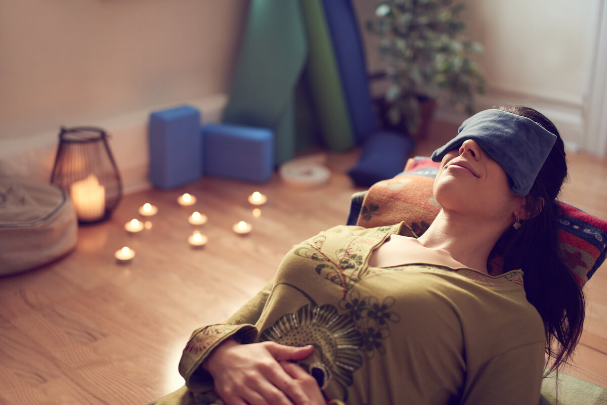 Serene lady relaxing and meditating on a yoga mat in a cosy house