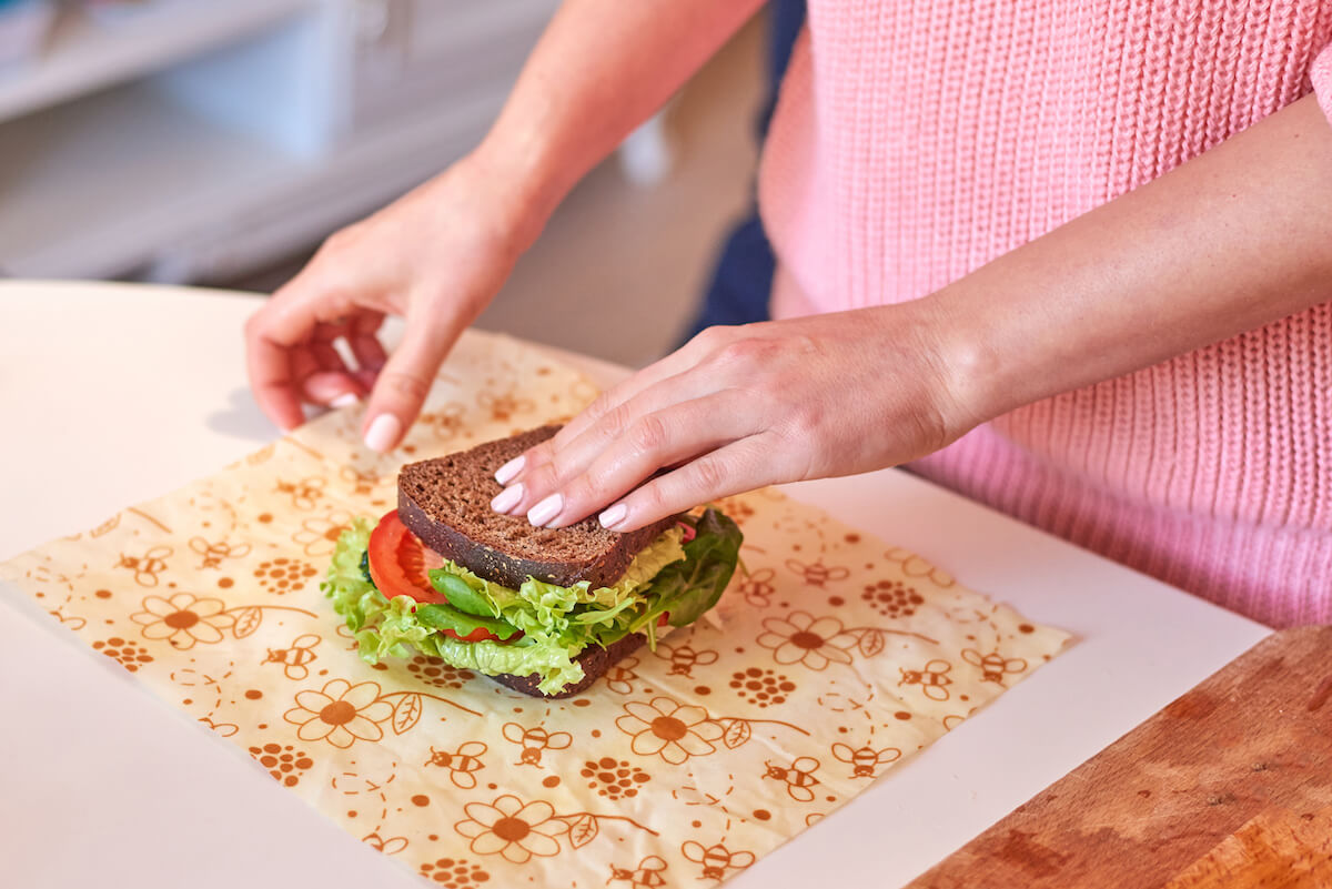 Woman hands wrapping a healthy sandwich in beeswax food wrap. 