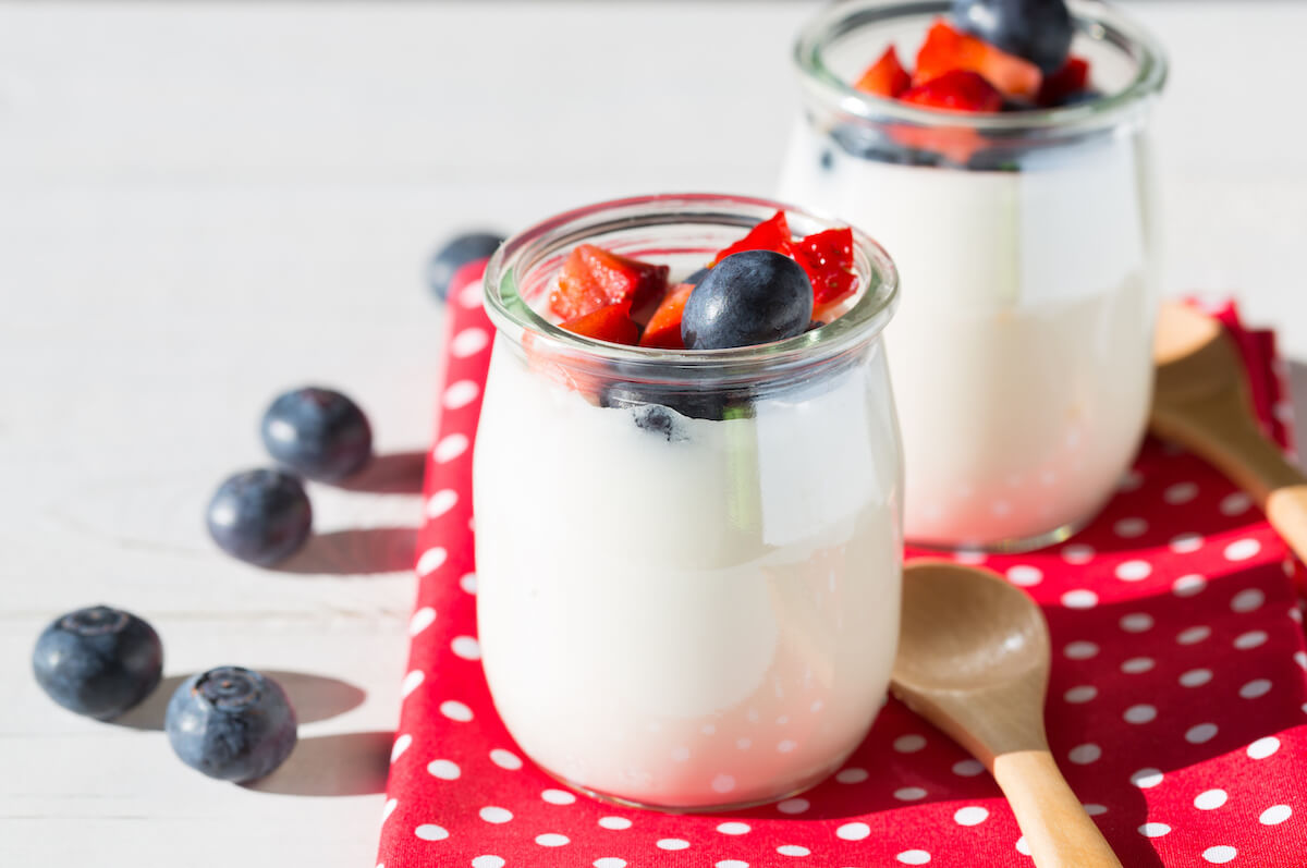 Yogurt with berries and strawberries into pieces on red table cloth