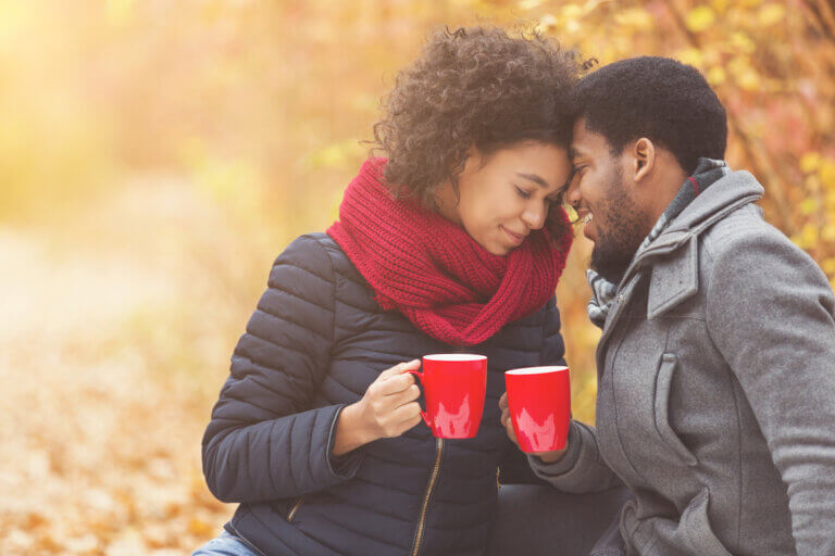 Couple drinking tea, spending time together in park in fall