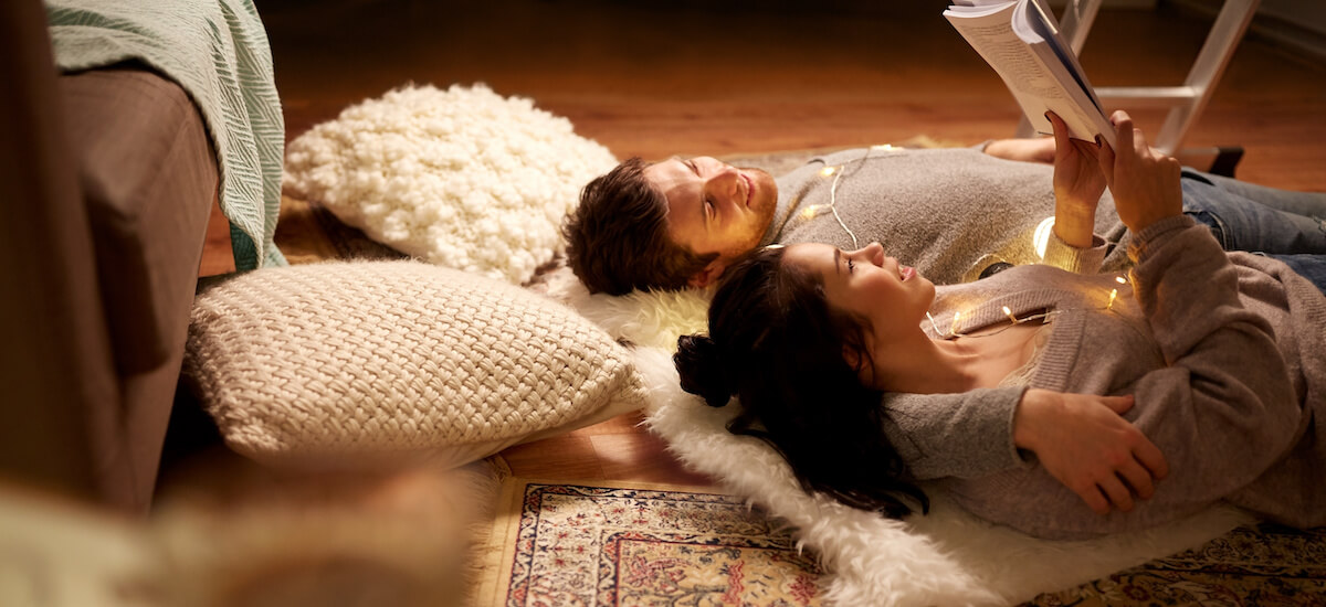 Happy couple at home on the floor reading stories