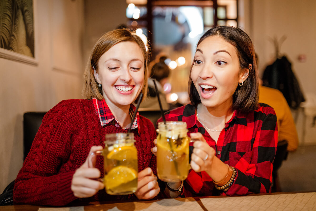 Happy friends drinking warm cider cocktail at bar