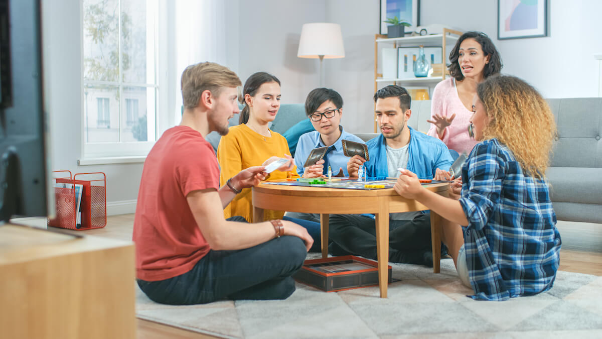 Diverse Group of Guys and Girls Playing in a Strategic Board Game with Cards and Dice.