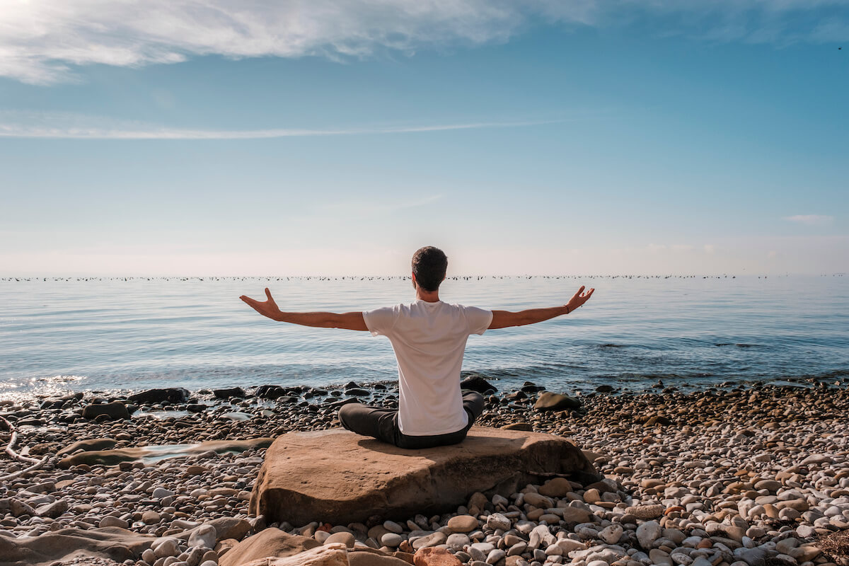 Young man practicing yoga meditation and breathwork outdoors by the sea