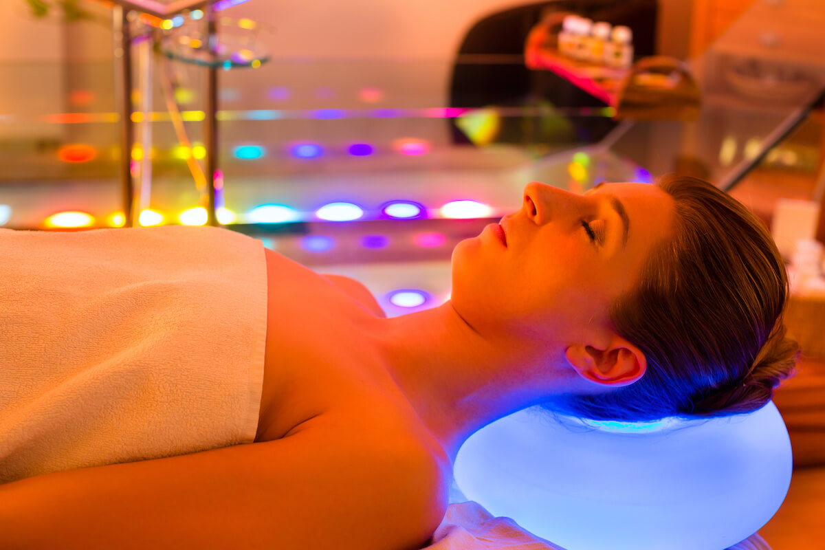 Woman enjoying therapy in spa with color therapy, colorful lights stimulating the psyche