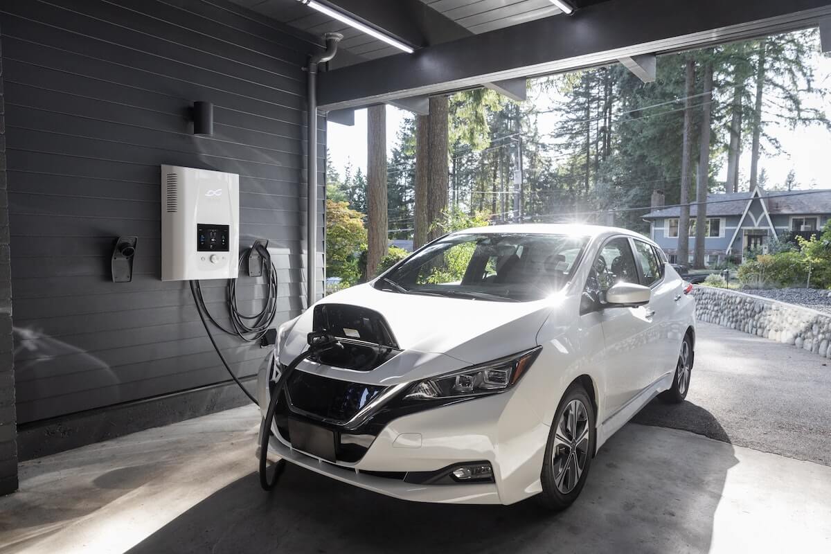 White electric car being charged in garage.