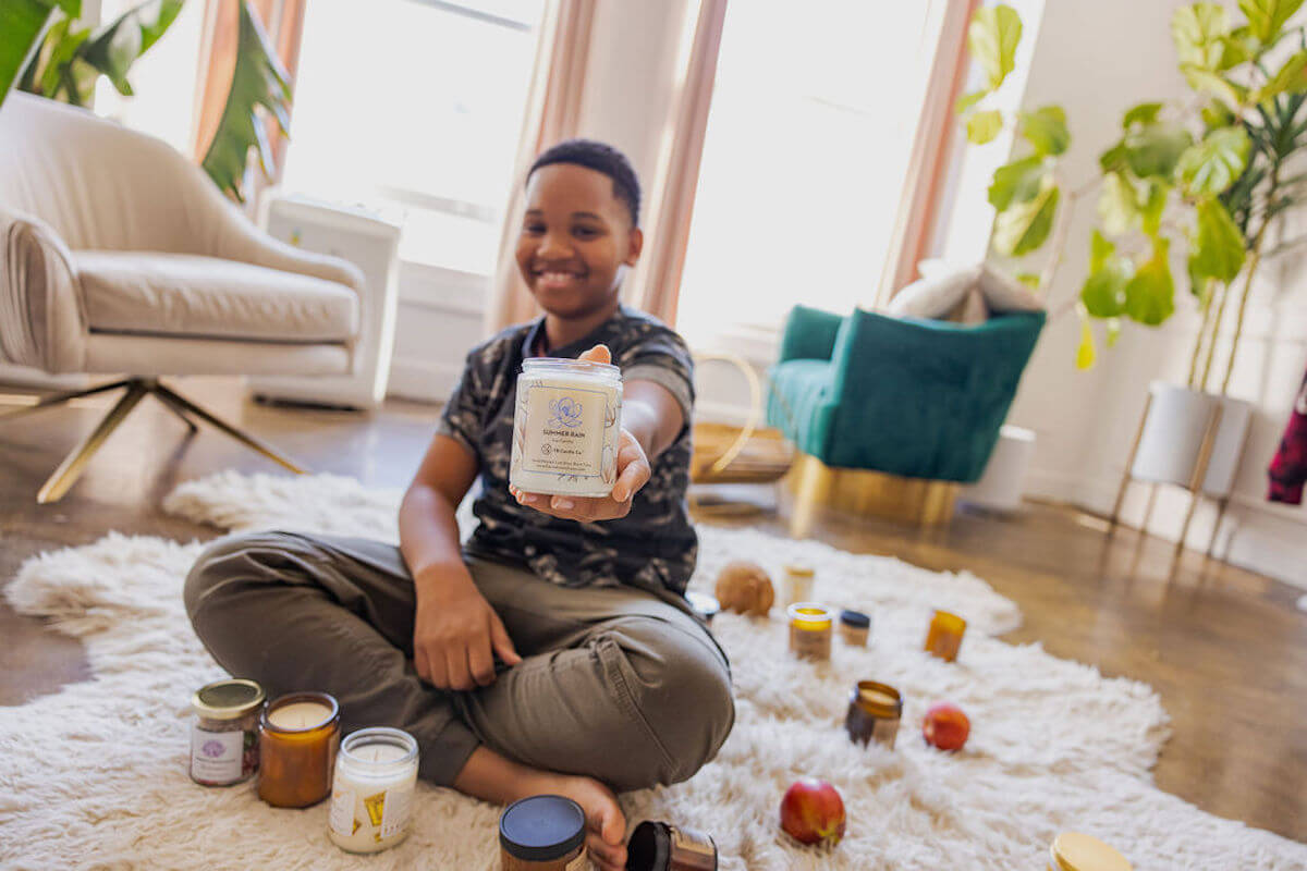 Youngest brother of Frères Branchiaux Candle Co. holding a candle from product line. 