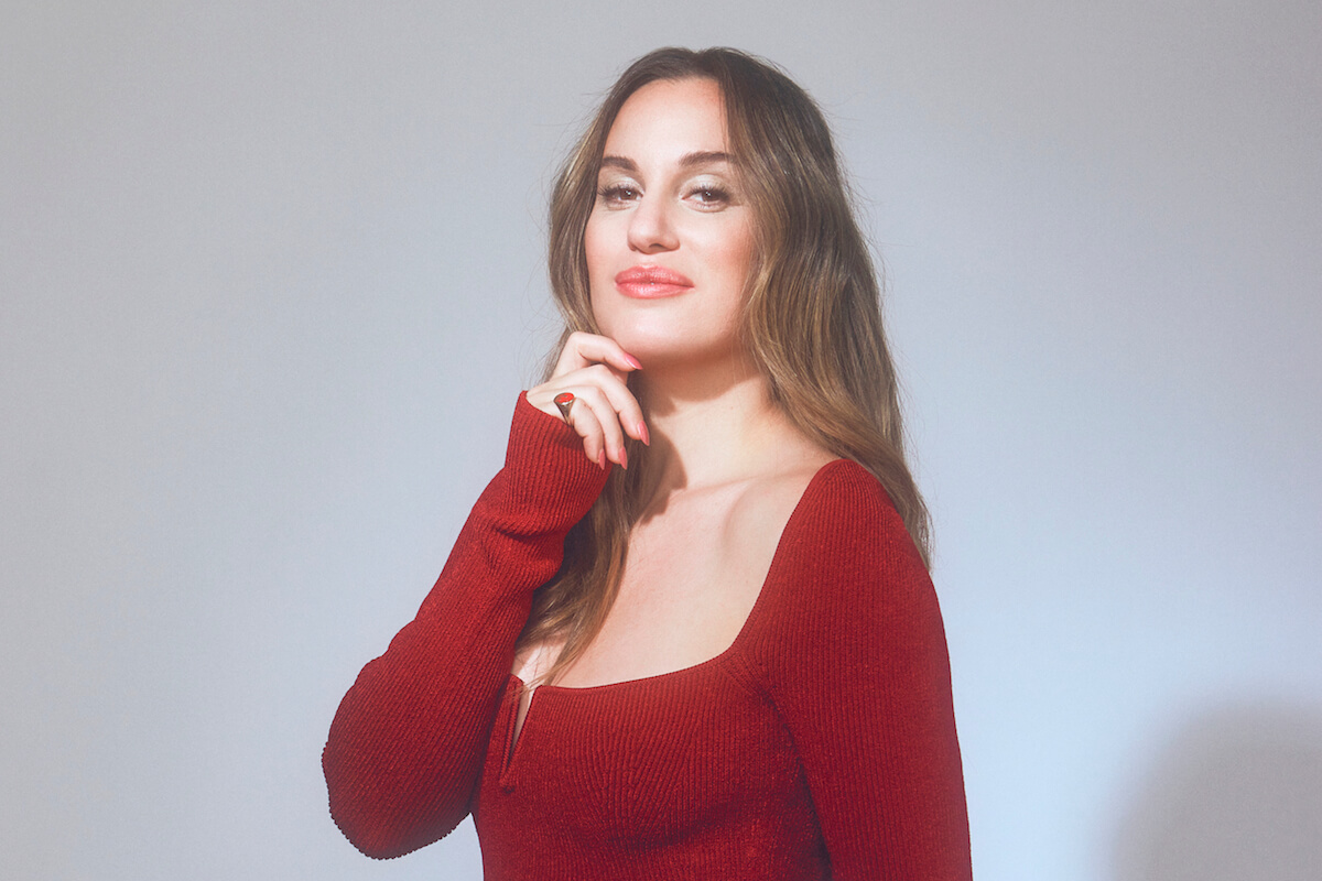 Comedian Hannah Berner wearing red sweater and smiling.