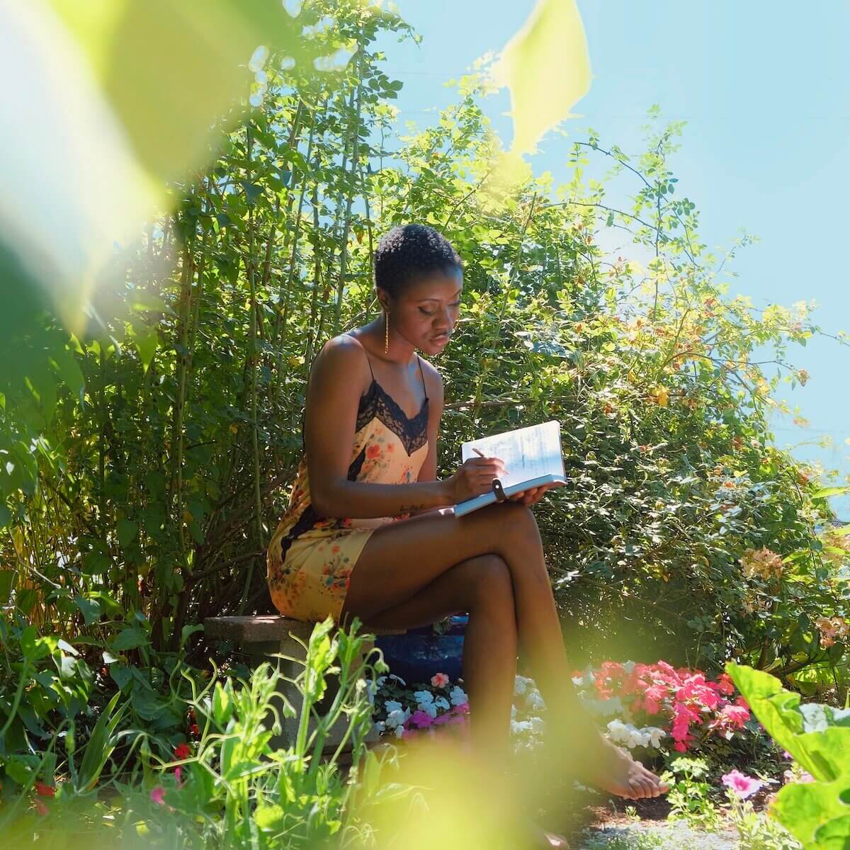 Emerald Osagie sitting in a garden reading.