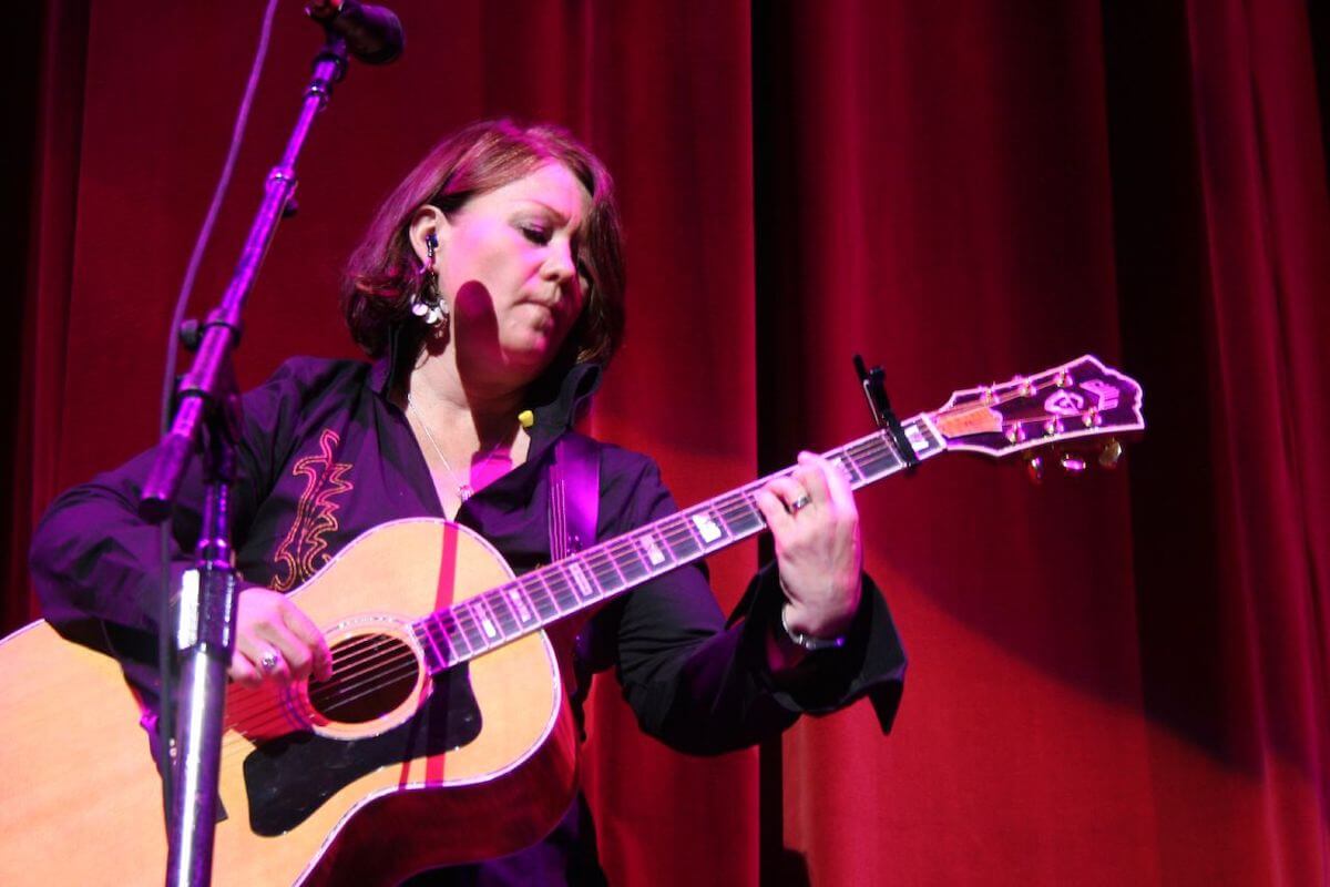 Jann Arden on stage playing guitar. 